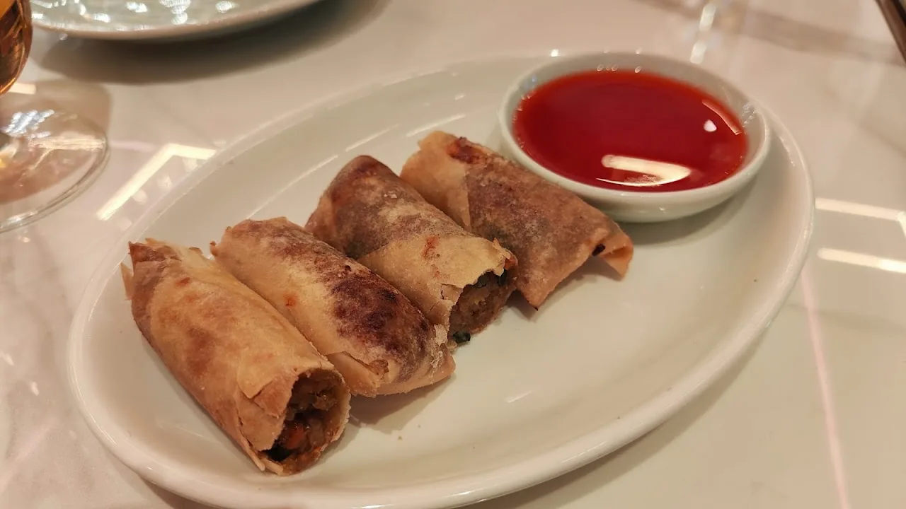 Two fried spring rolls served with red dipping sauce