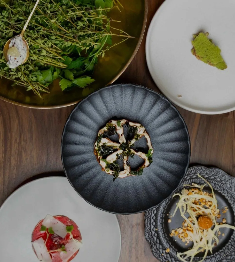 An overhead view of several plated dishes on a dark wooden table