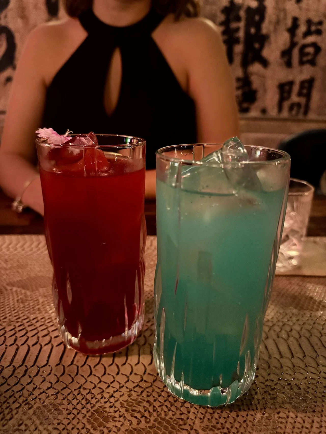 Two cocktails, one red and one blue, served in tall glasses at a table