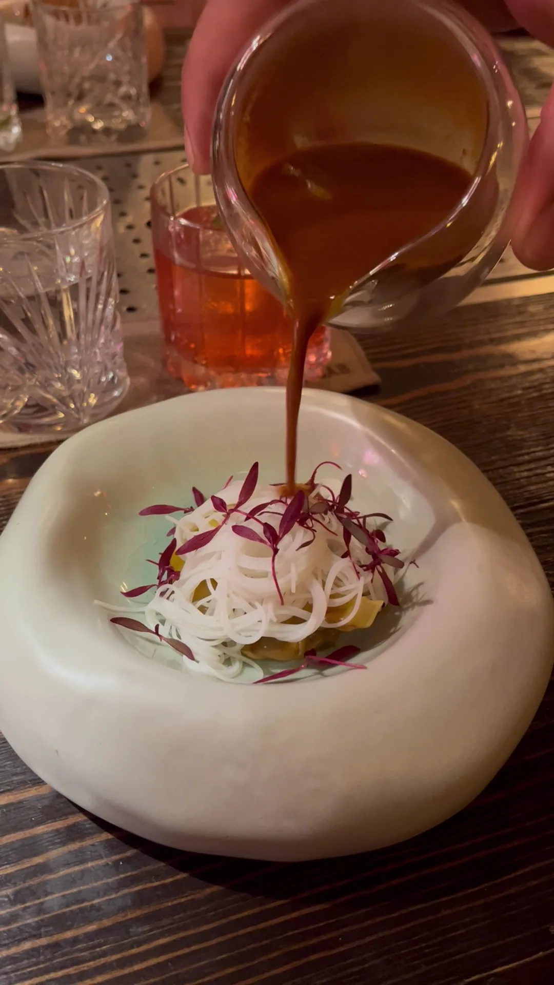 Sauce being poured over a dish with pickled onions in a stone bowl