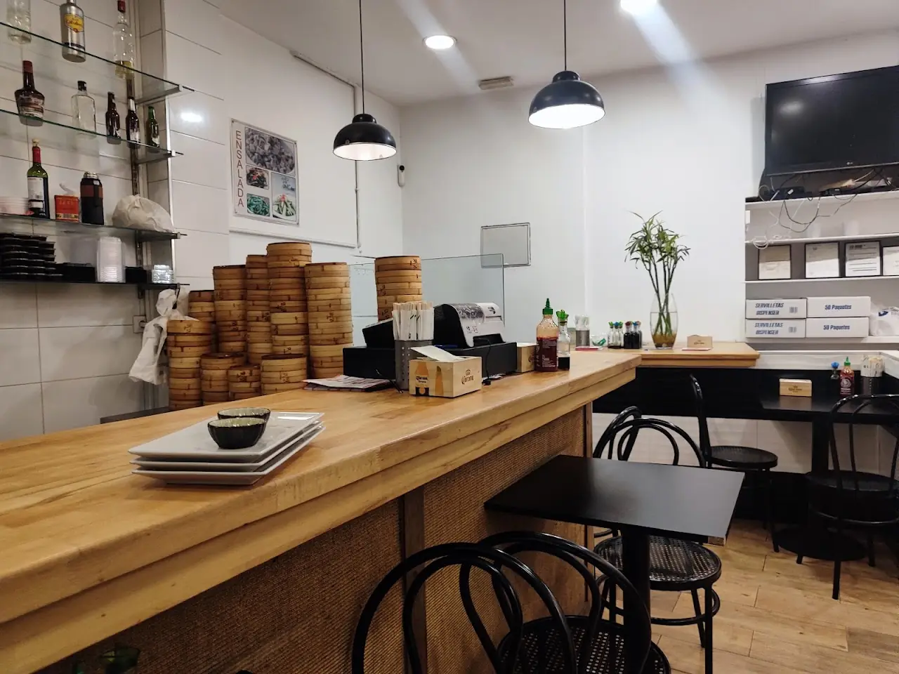 Gyoza Go!'s wooden counter with stacks of bamboo steamers and pendant lights