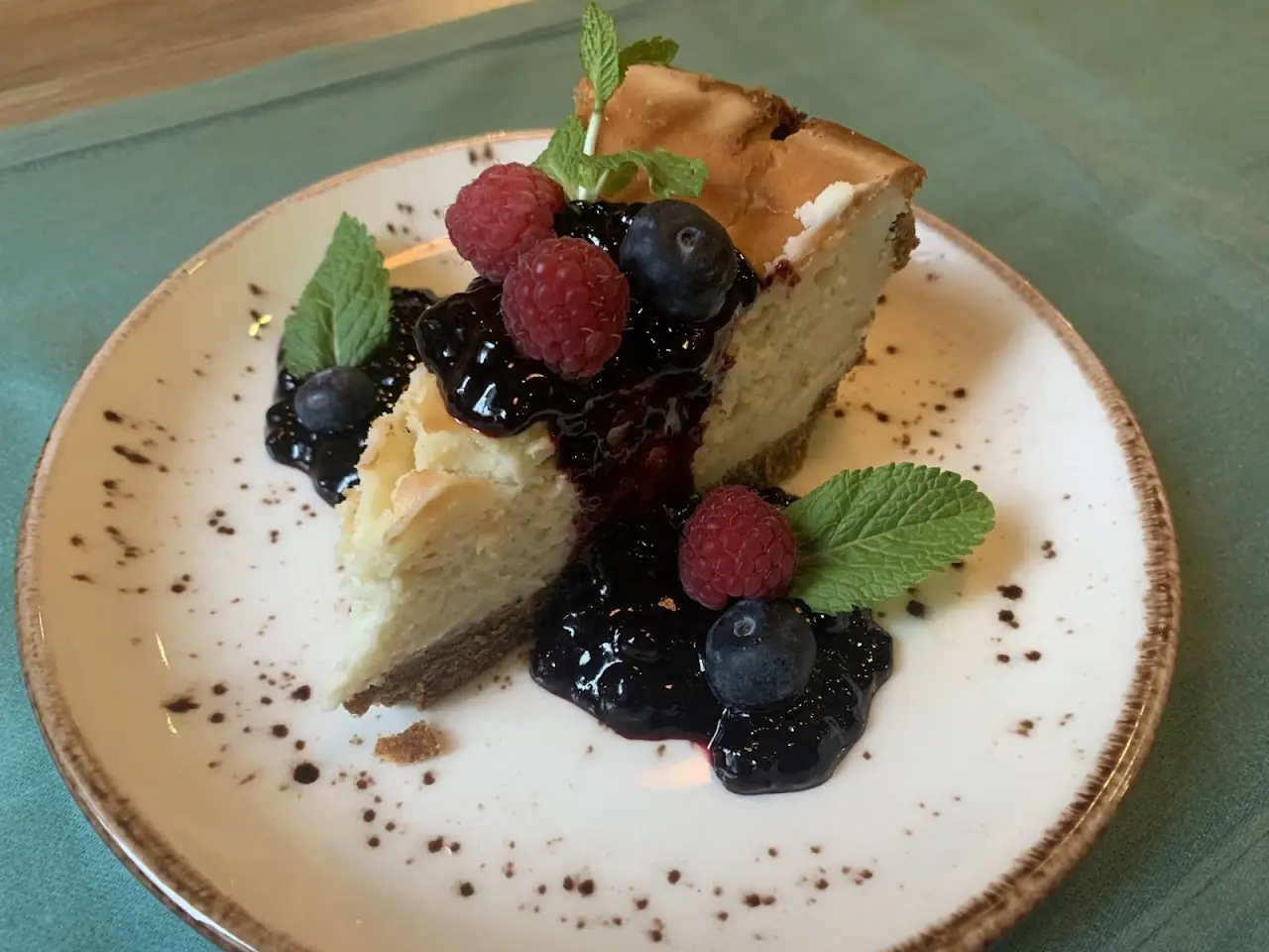 A slice of cheesecake topped with mixed berries and mint.