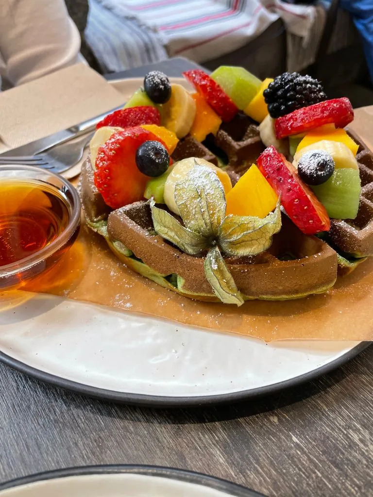 A waffle topped with fresh berries and kiwi slices
