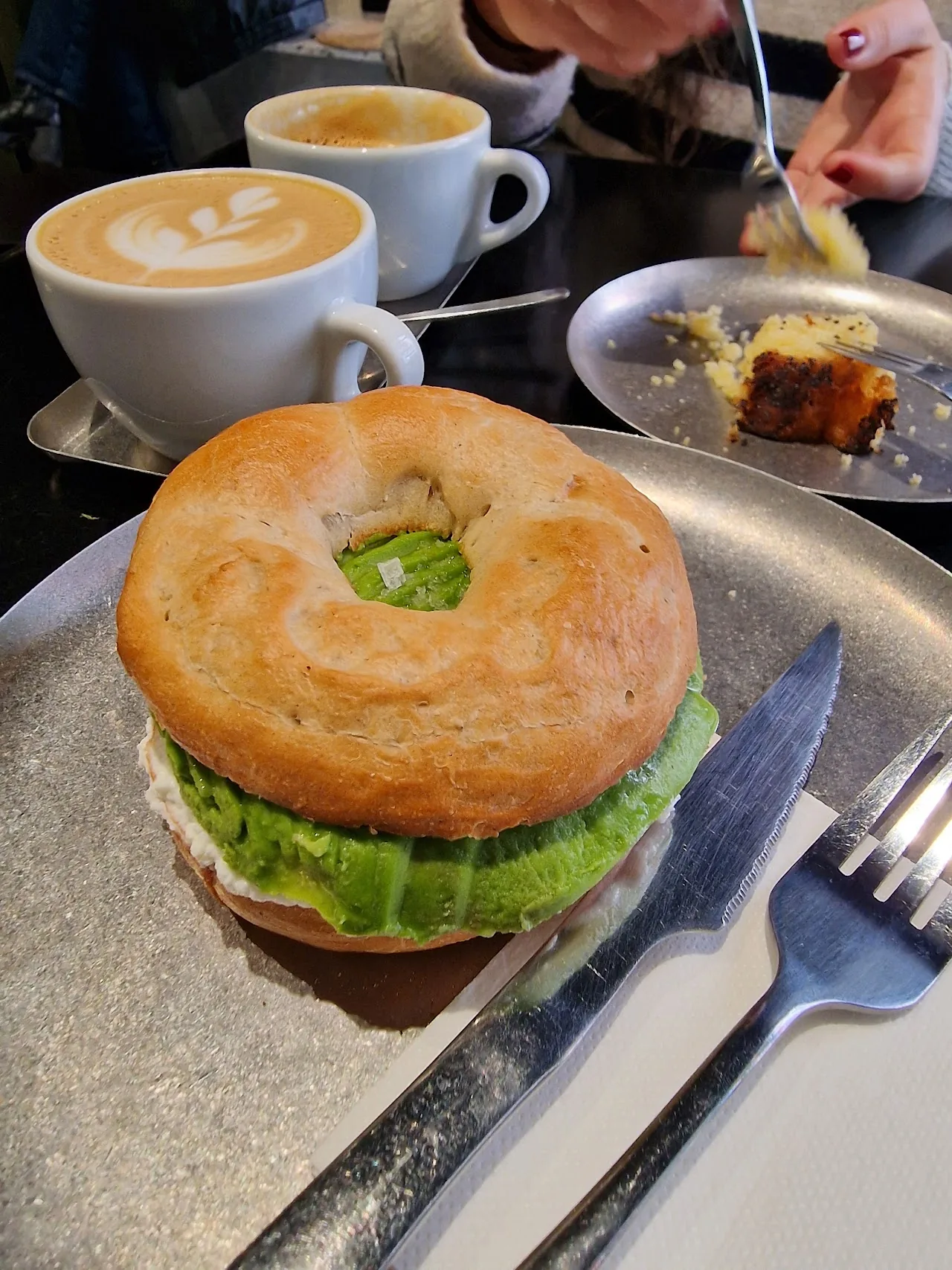 A bagel sandwich with lettuce and salmon, cut open on a plate