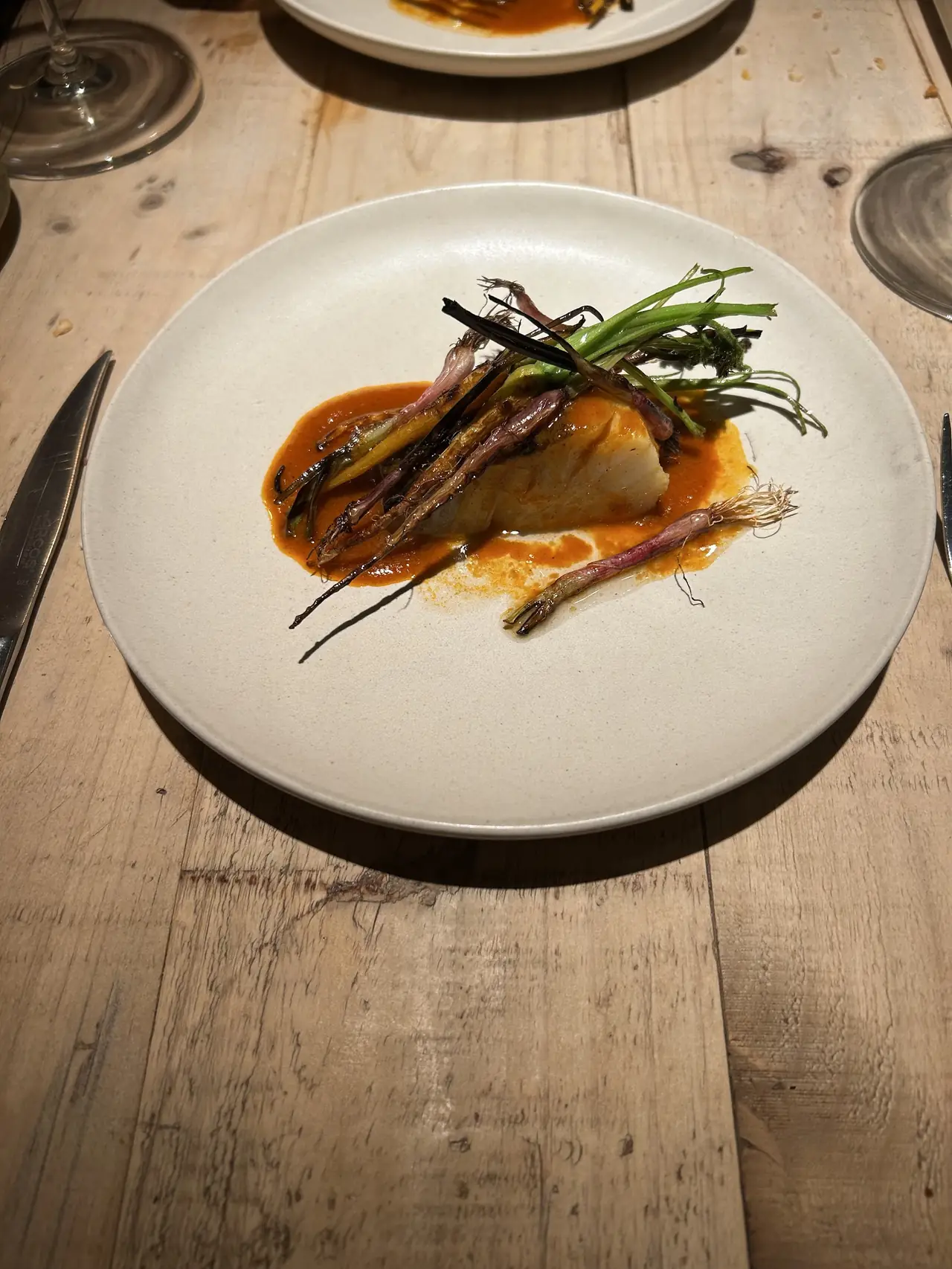 White fish fillet with charred spring onions on orange sauce