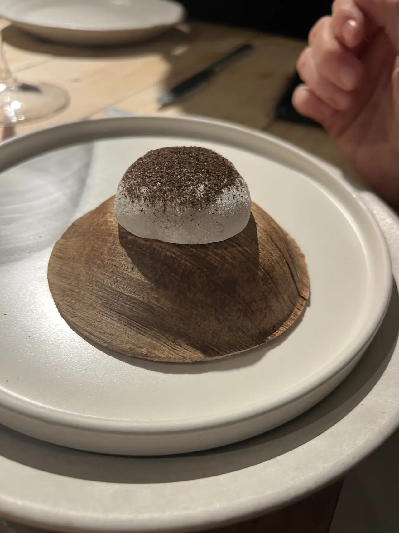 Dome-shaped dessert dusted with dark cocoa on a wood plate