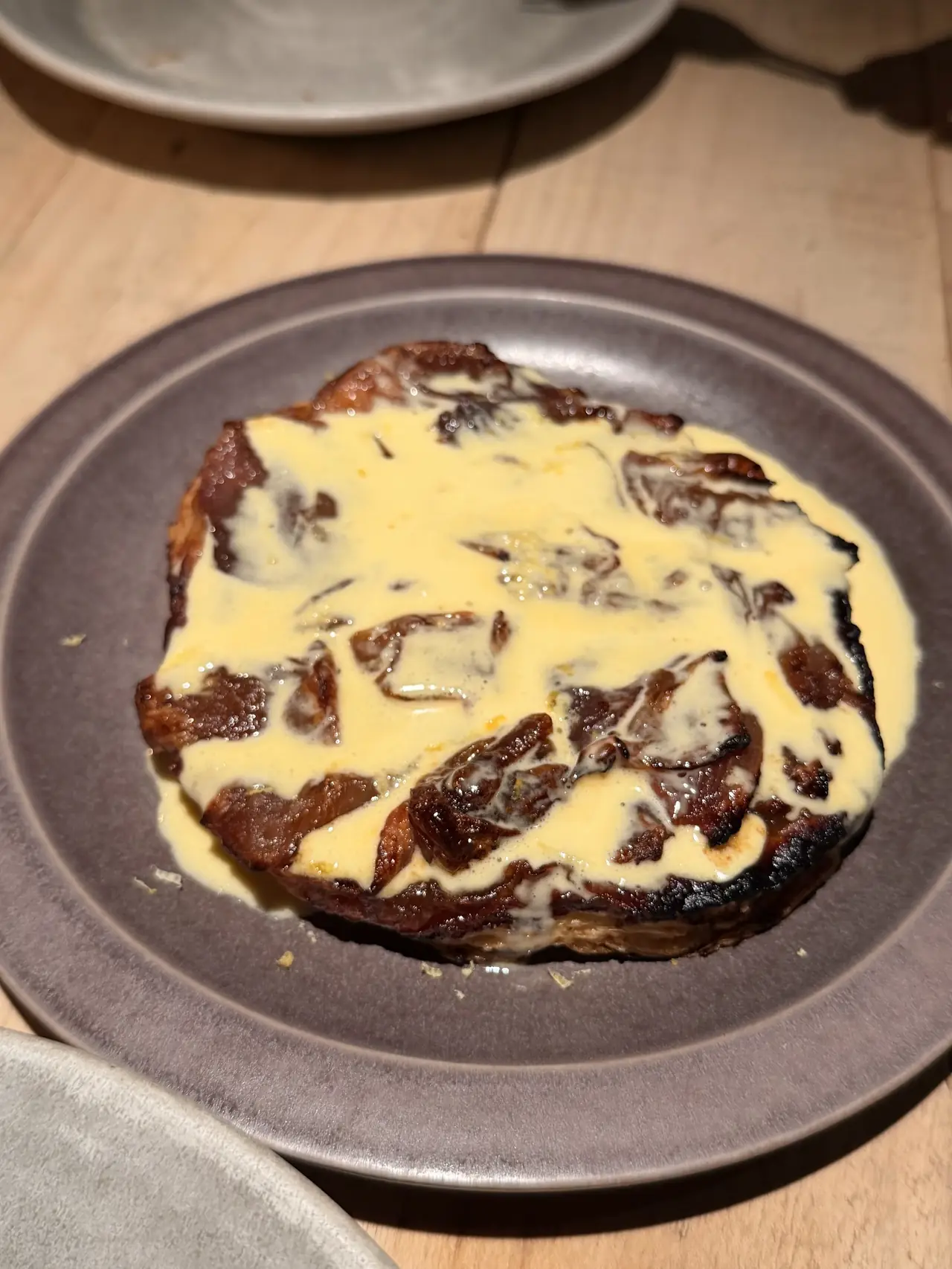 Charred meat round on a plate topped with creamy pale yellow sauce