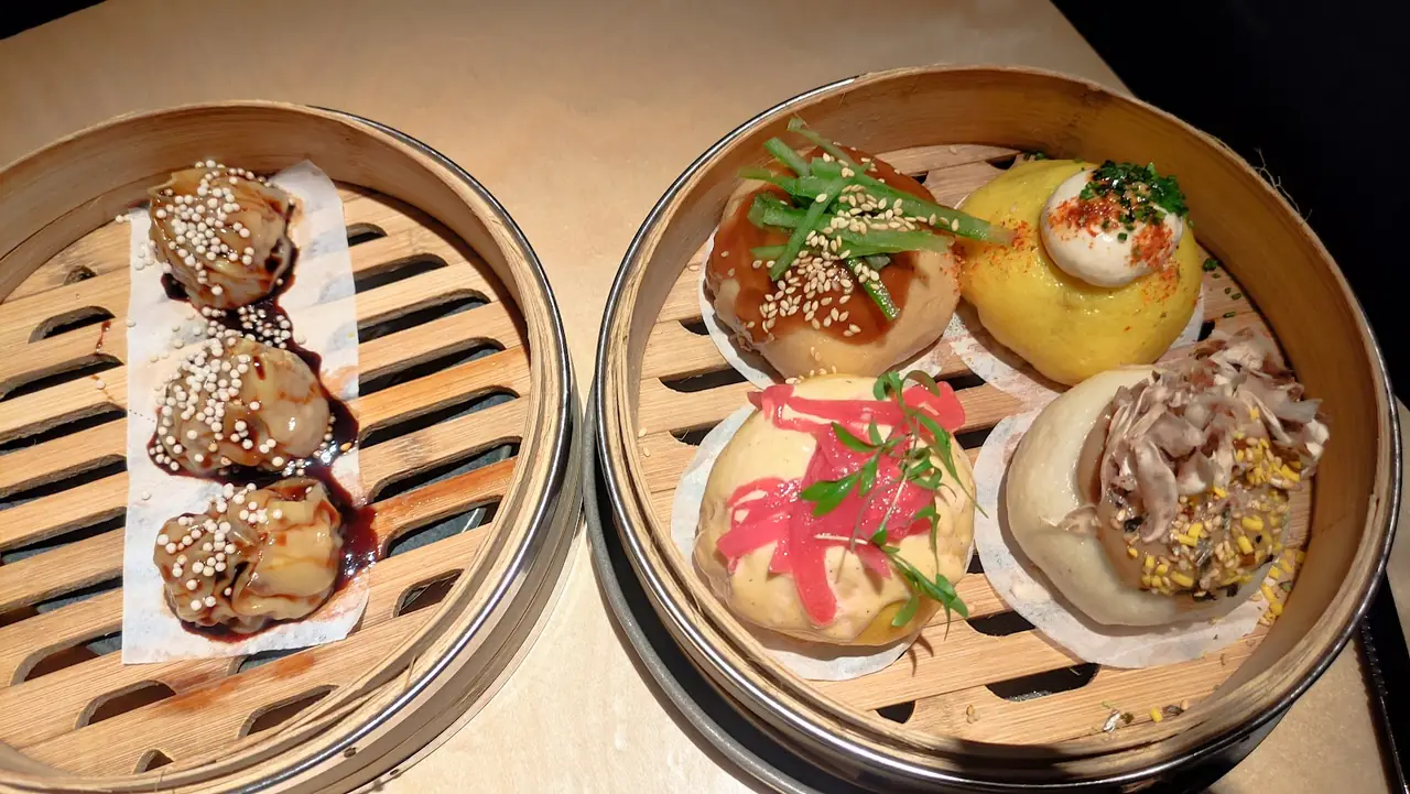 Steamed dumplings and bao buns with varied toppings in bamboo steamers