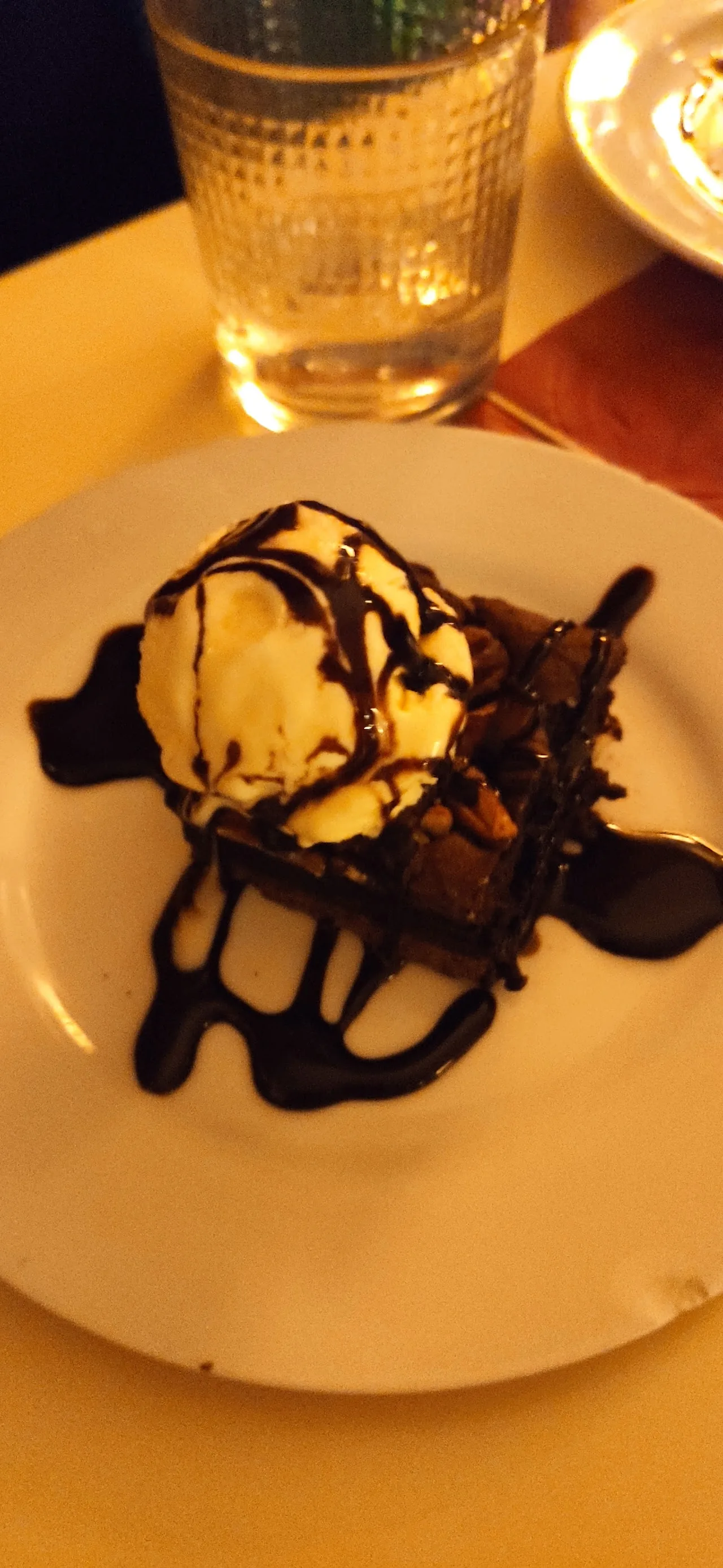 A dessert with a scoop of ice cream drizzled with chocolate sauce