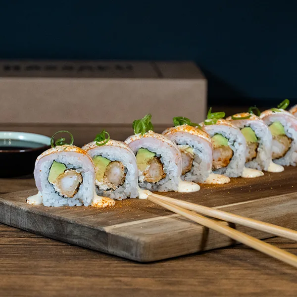A platter of sushi rolls with chopsticks on a wooden board