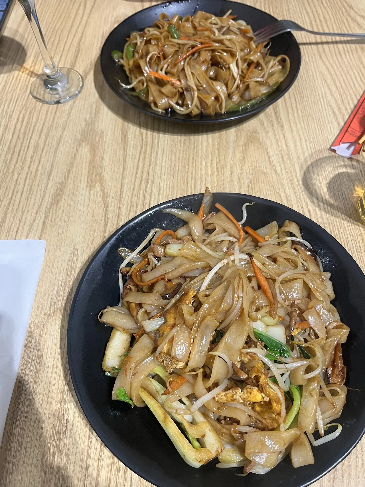 Two plates of stir-fried noodles with vegetables