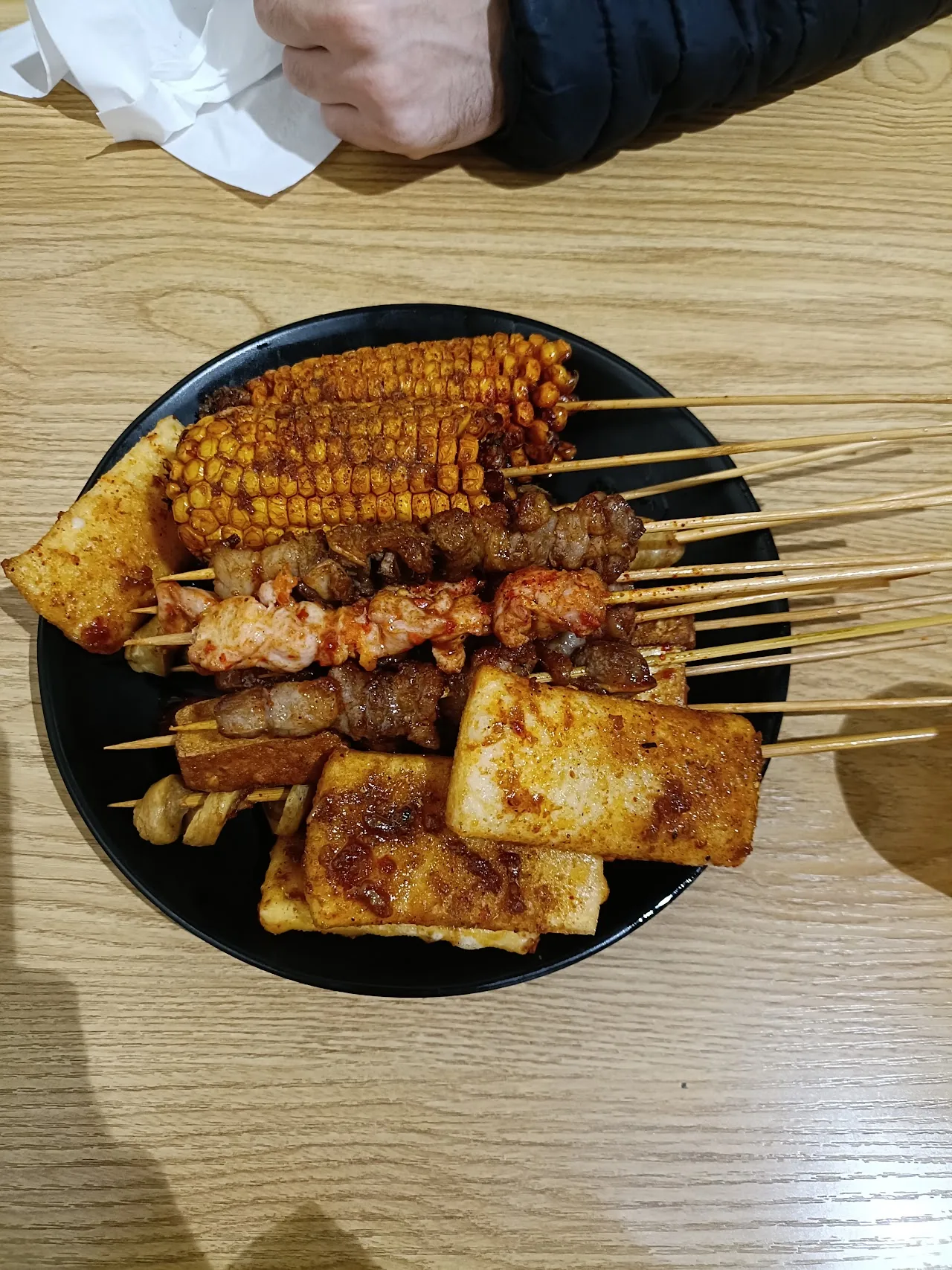 A plate of grilled skewers with corn on the cob
