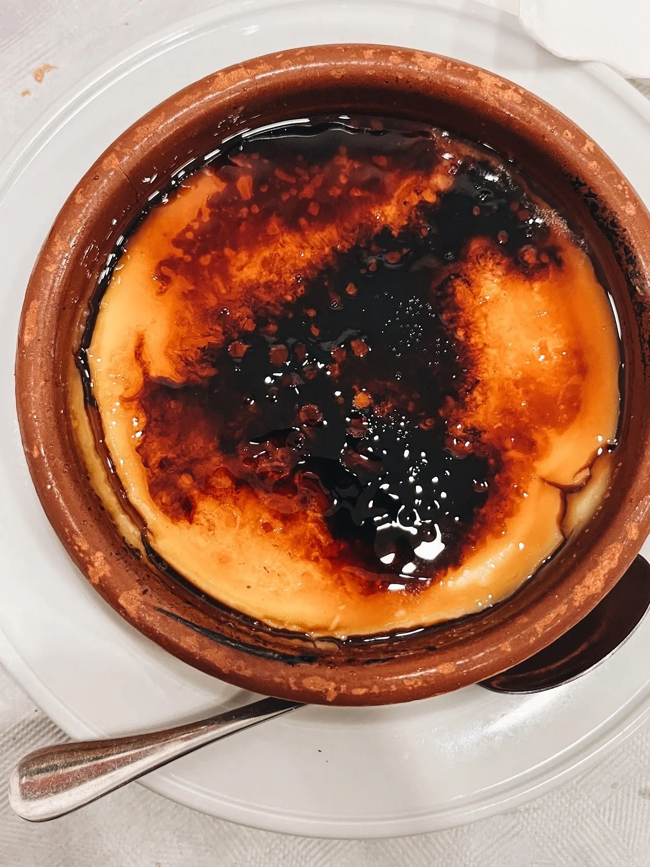 A brown clay dish of custard with a caramelised top