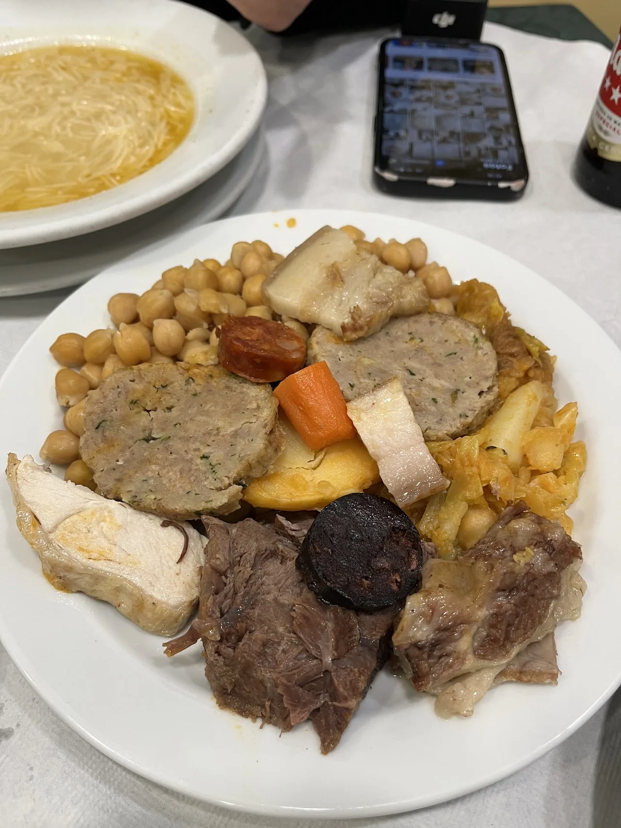 A plate of cocido madrileno with chickpeas, meats, and vegetables