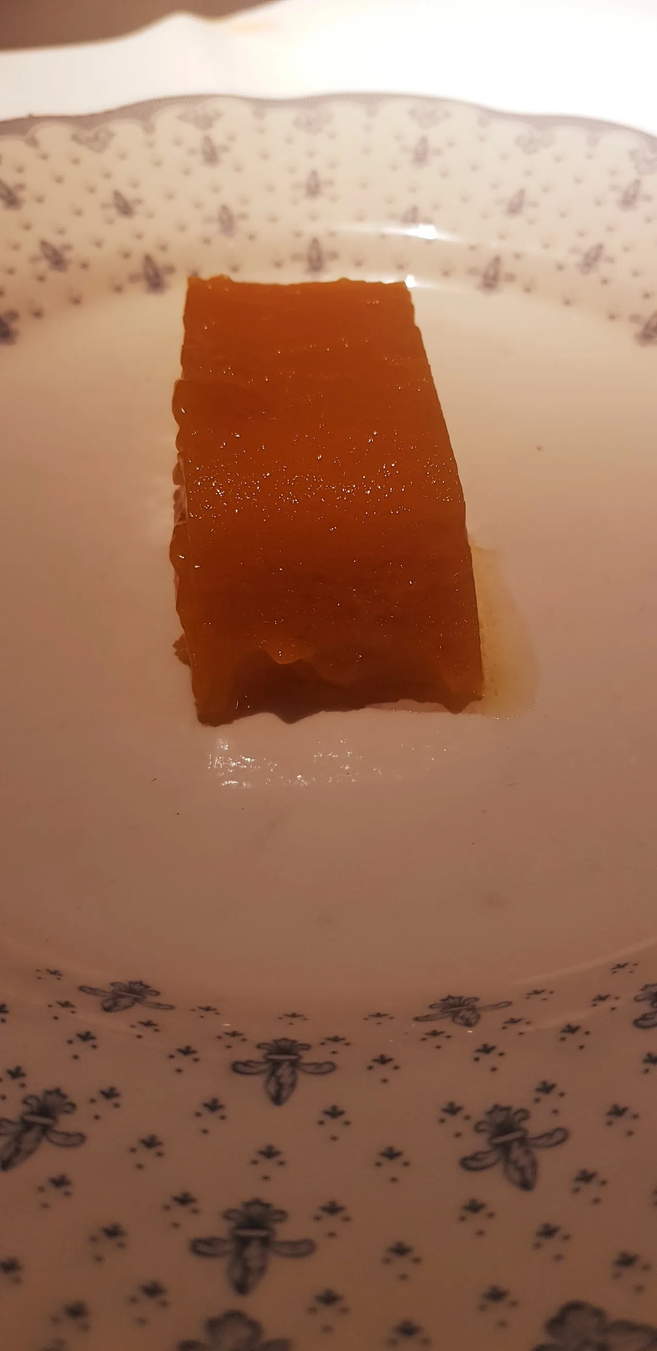 A square orange geleee or terrine on a plate