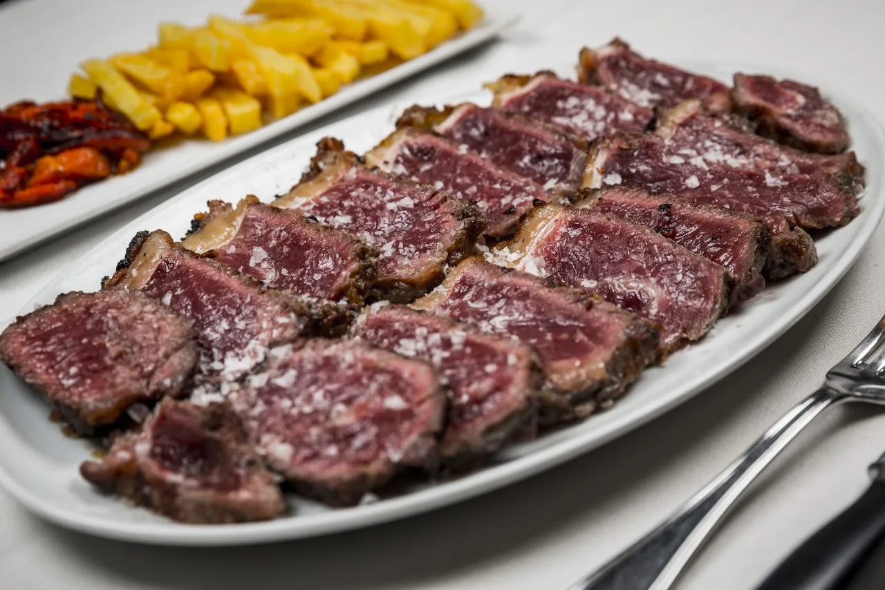 Sliced grilled beef with fries on a platter