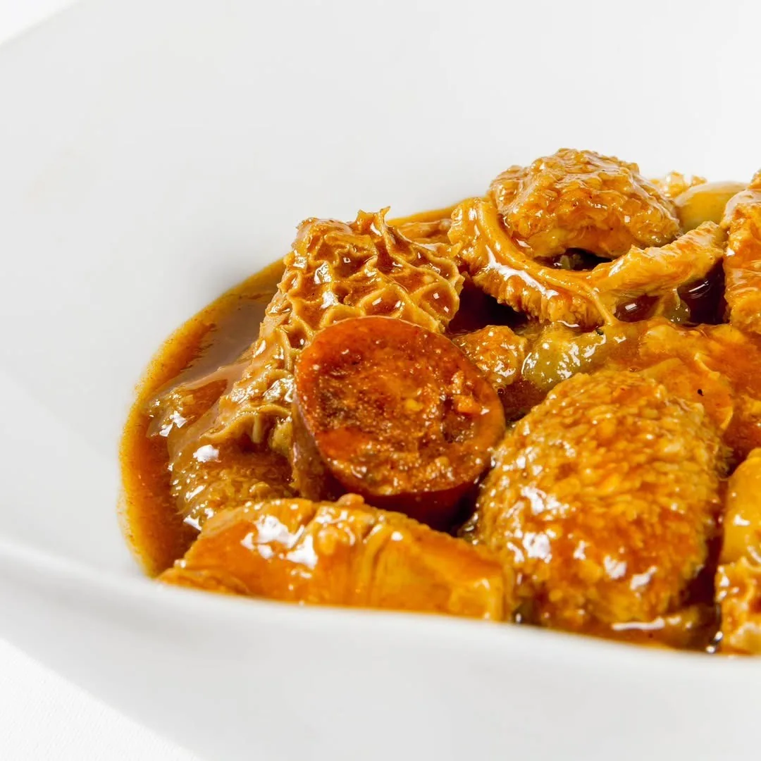 Tripe stew with slices of sausage in a rich orange sauce