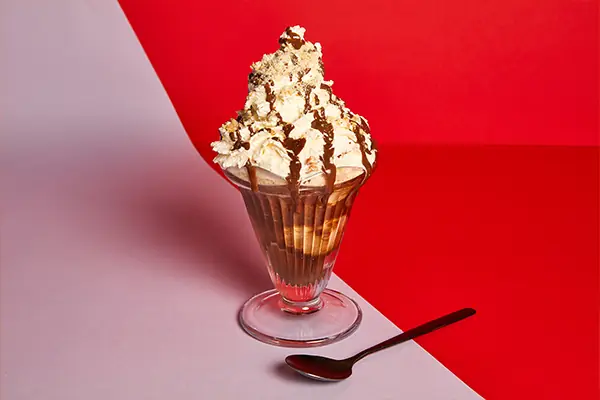 Sundae dessert with whipped cream, chocolate drizzle and cookie crumble in a glass at Hideout Burger
