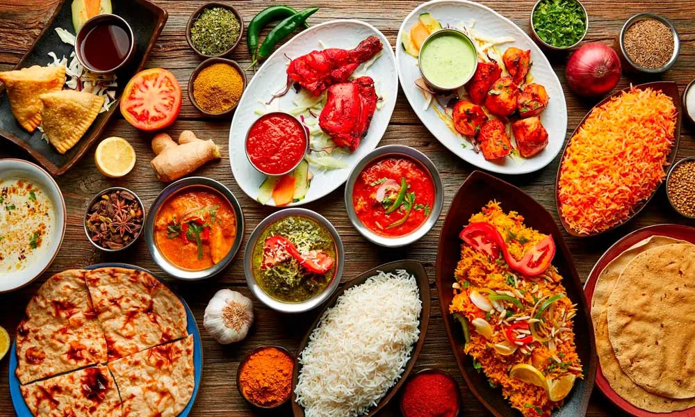 An overhead spread of Nepalese dishes including rice, pizza, curries, and salads