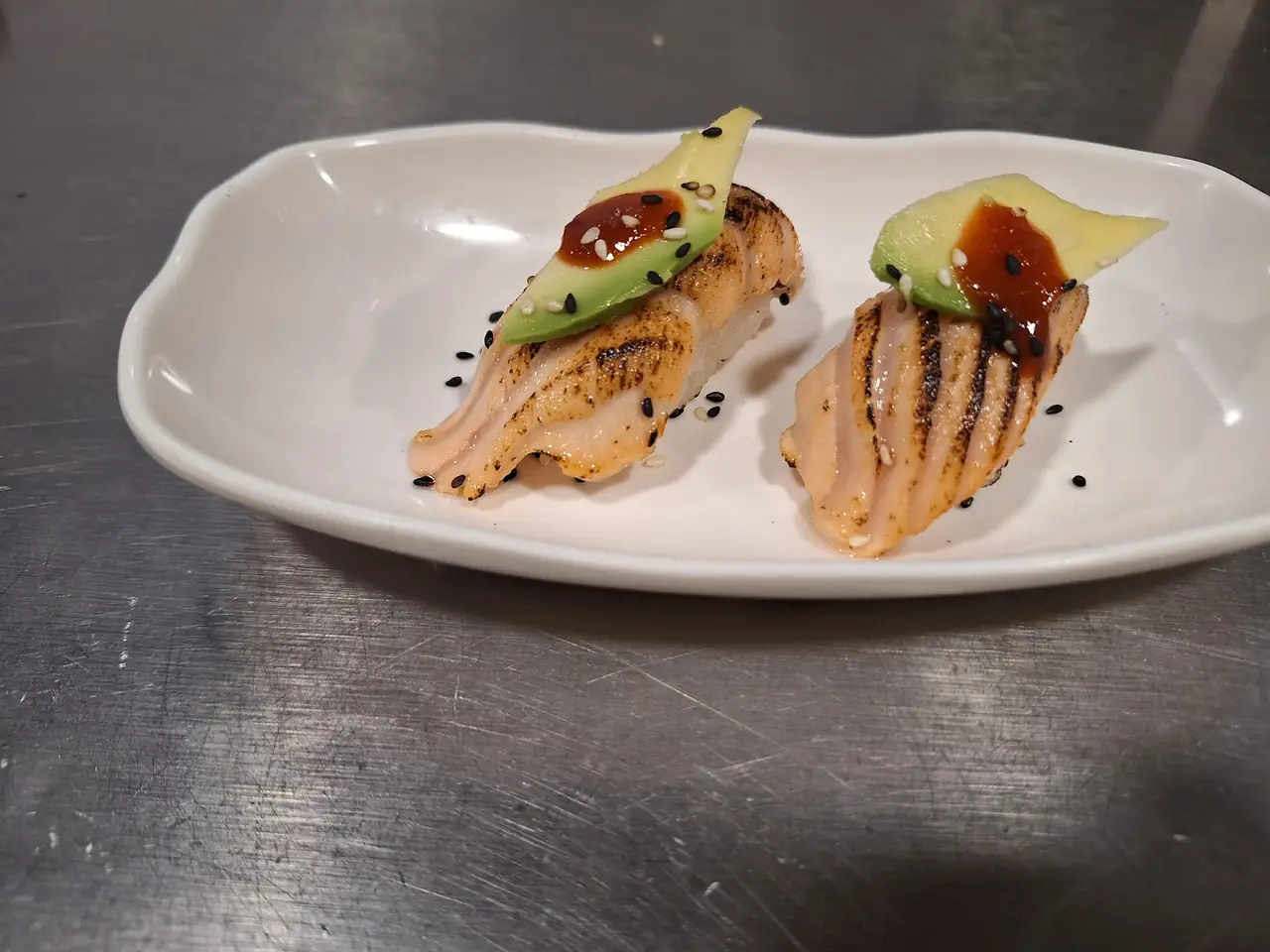 Nigiri sushi with seared salmon, avocado and sesame seeds