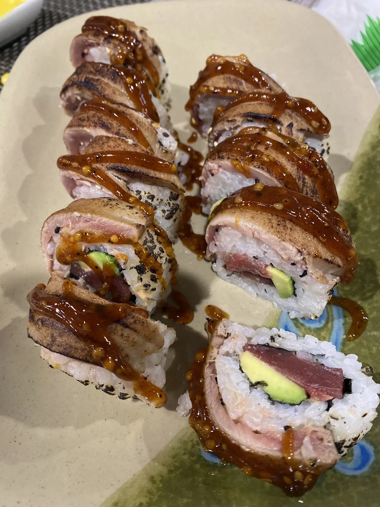 Sushi roll topped with seared tuna and drizzled sauce