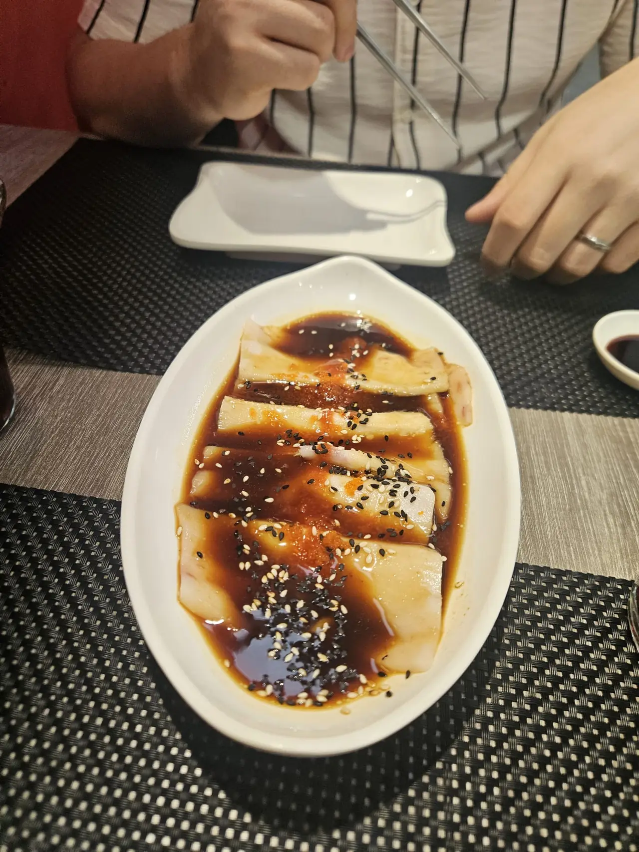 Plated dish drizzled with sauce and sesame seeds on the table