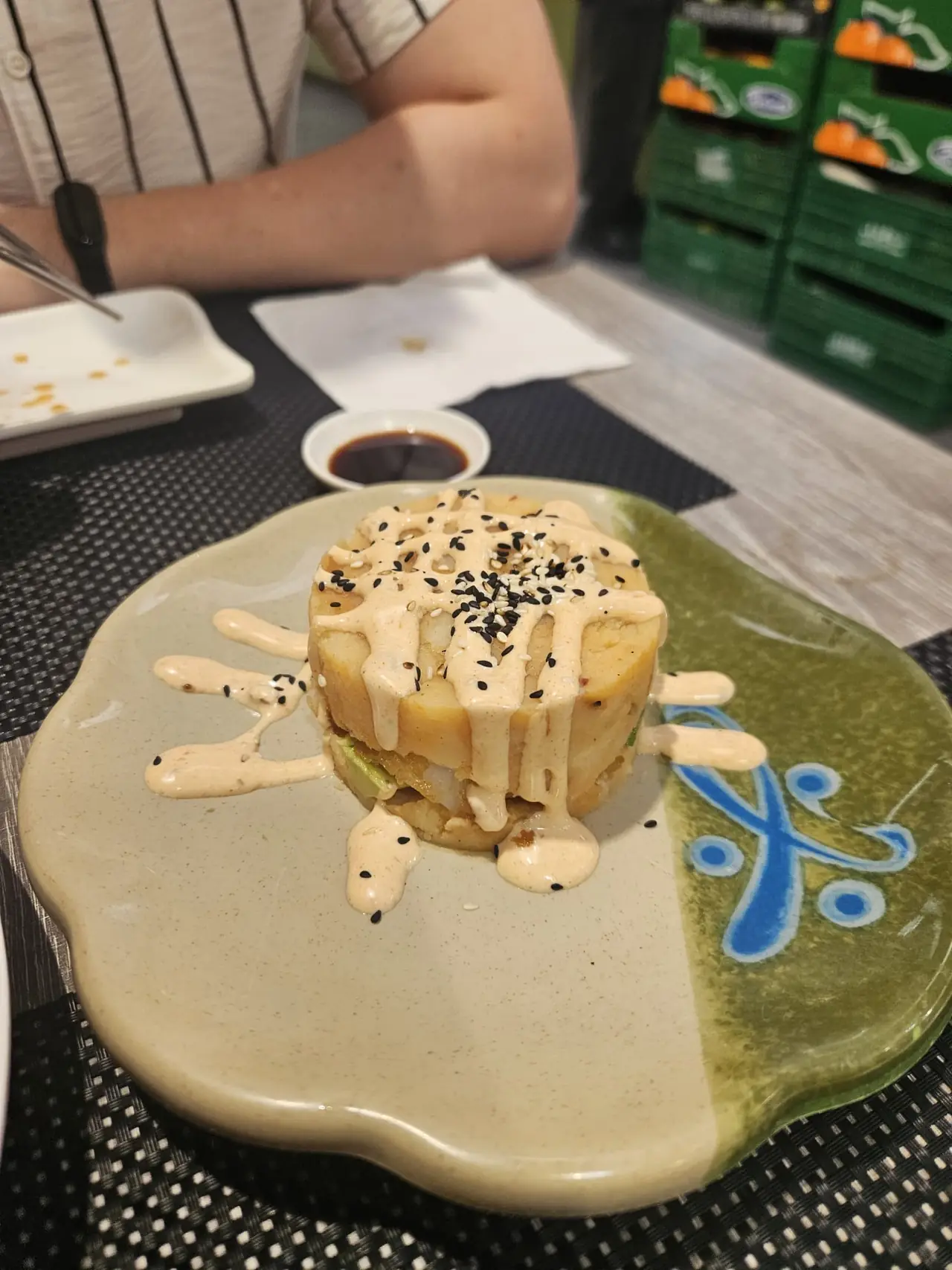 Stacked crispy rice sushi tower drizzled with spicy mayo and sesame seeds