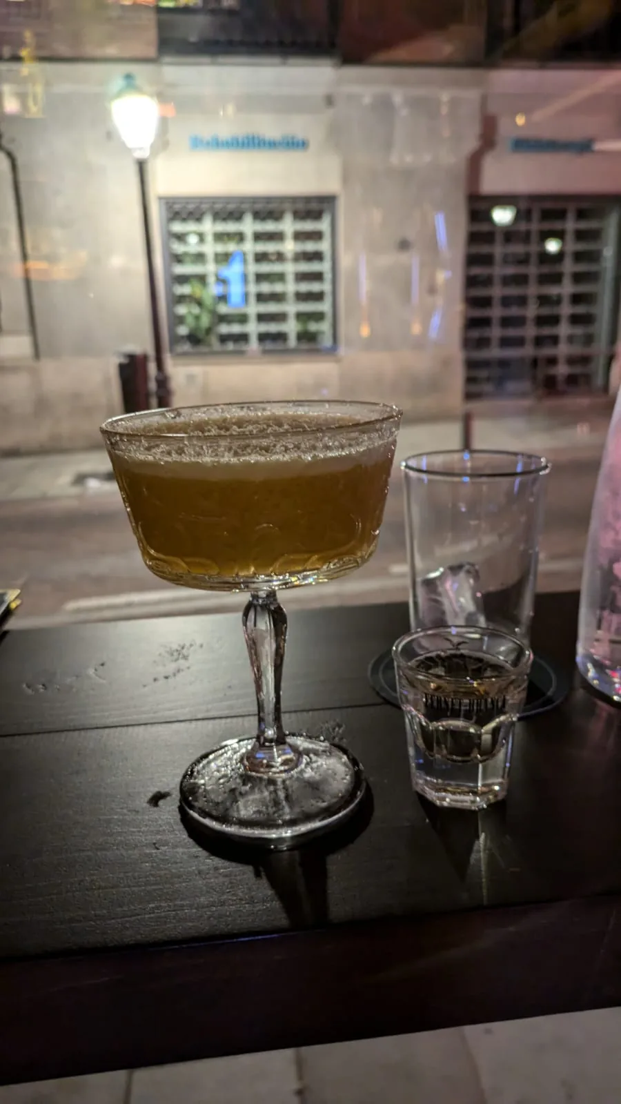 A garnished cocktail on an outdoor ledge at night