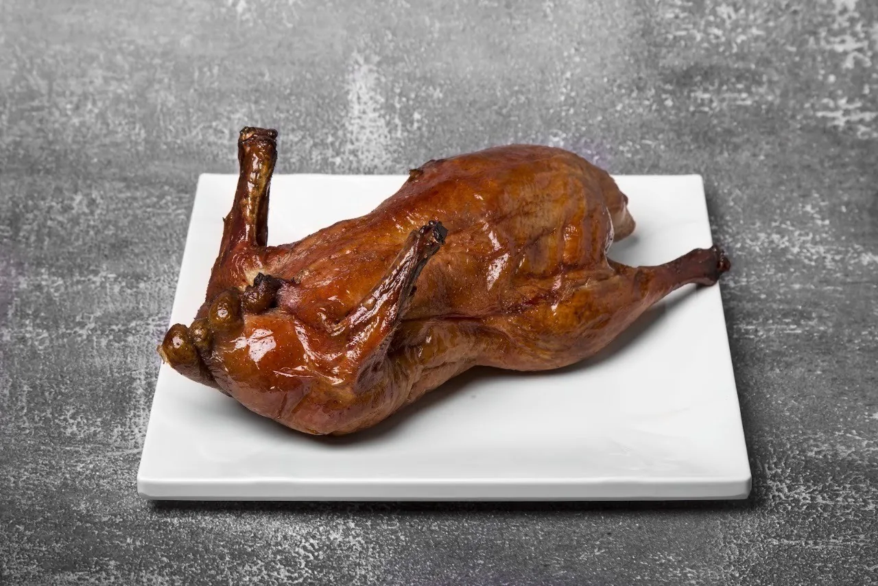 A roast duck on a square white plate