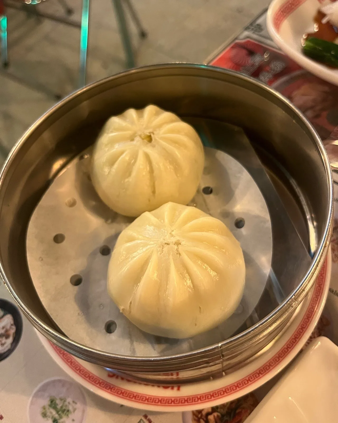 Two steamed buns in a metal steamer basket