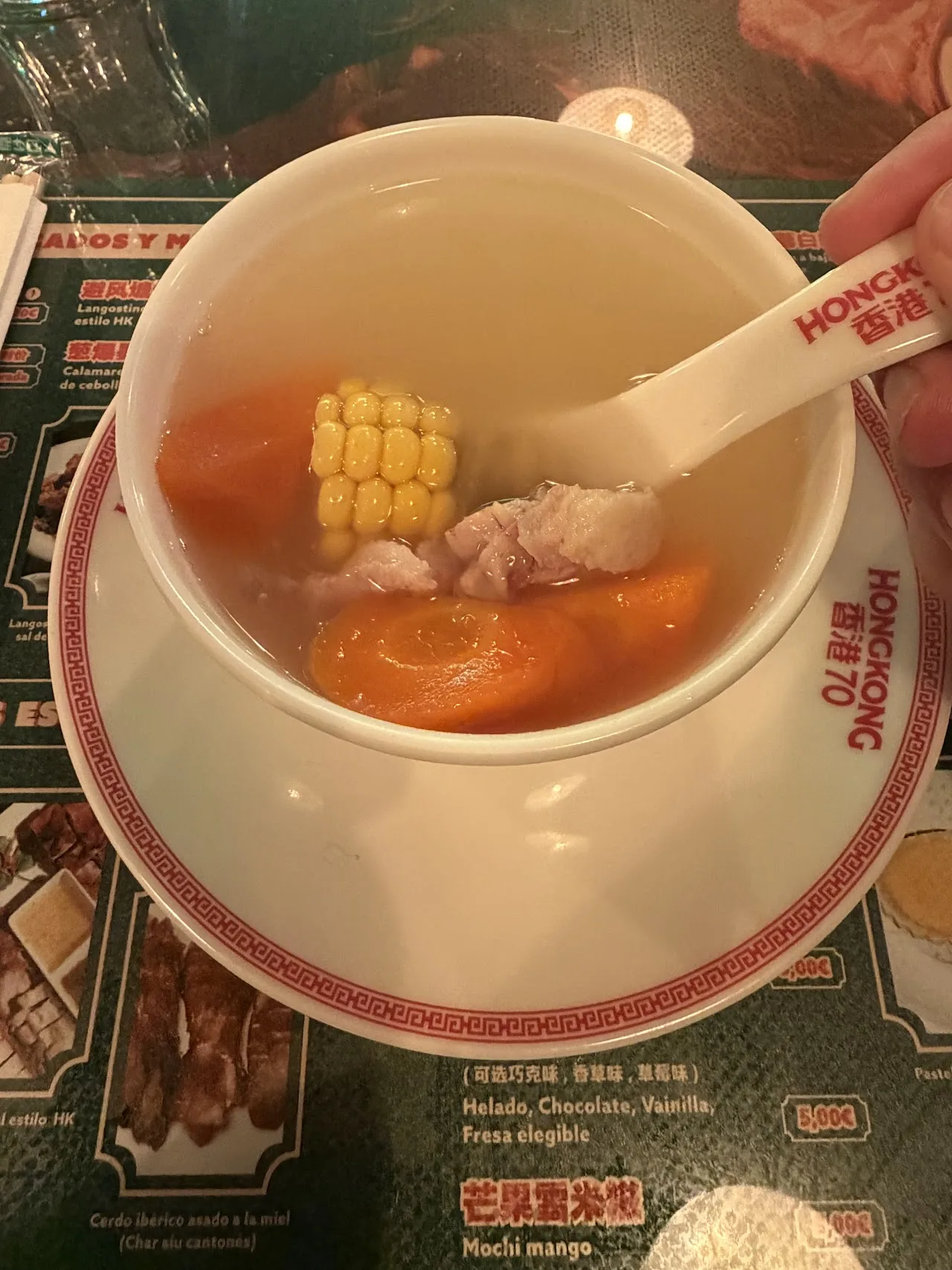 A bowl of soup with corn and meat pieces