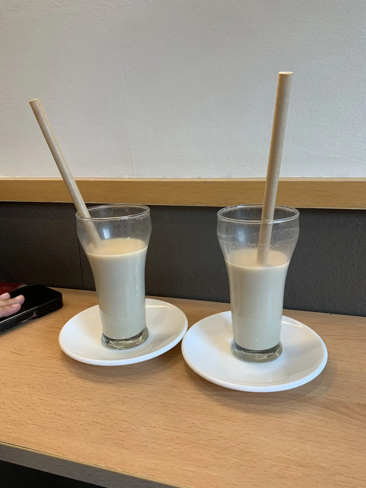 Two glasses of horchata with paper straws on saucers on a wooden counter