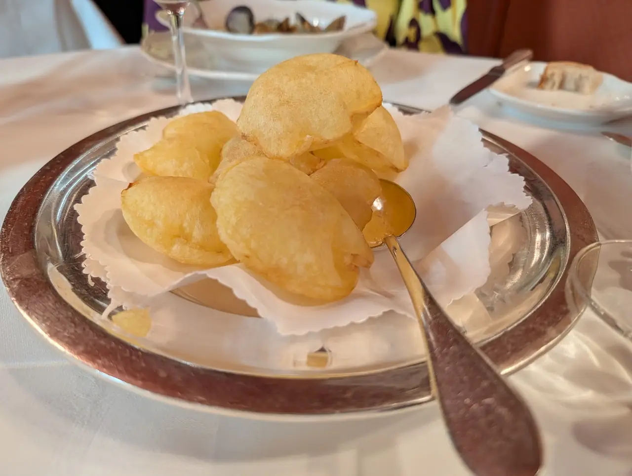 Puffed fried potato souffles served on paper in a silver dish
