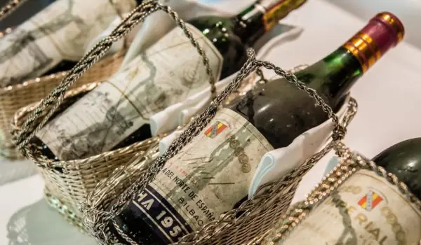 Wine bottles with aged labels presented in silver tableside serving baskets