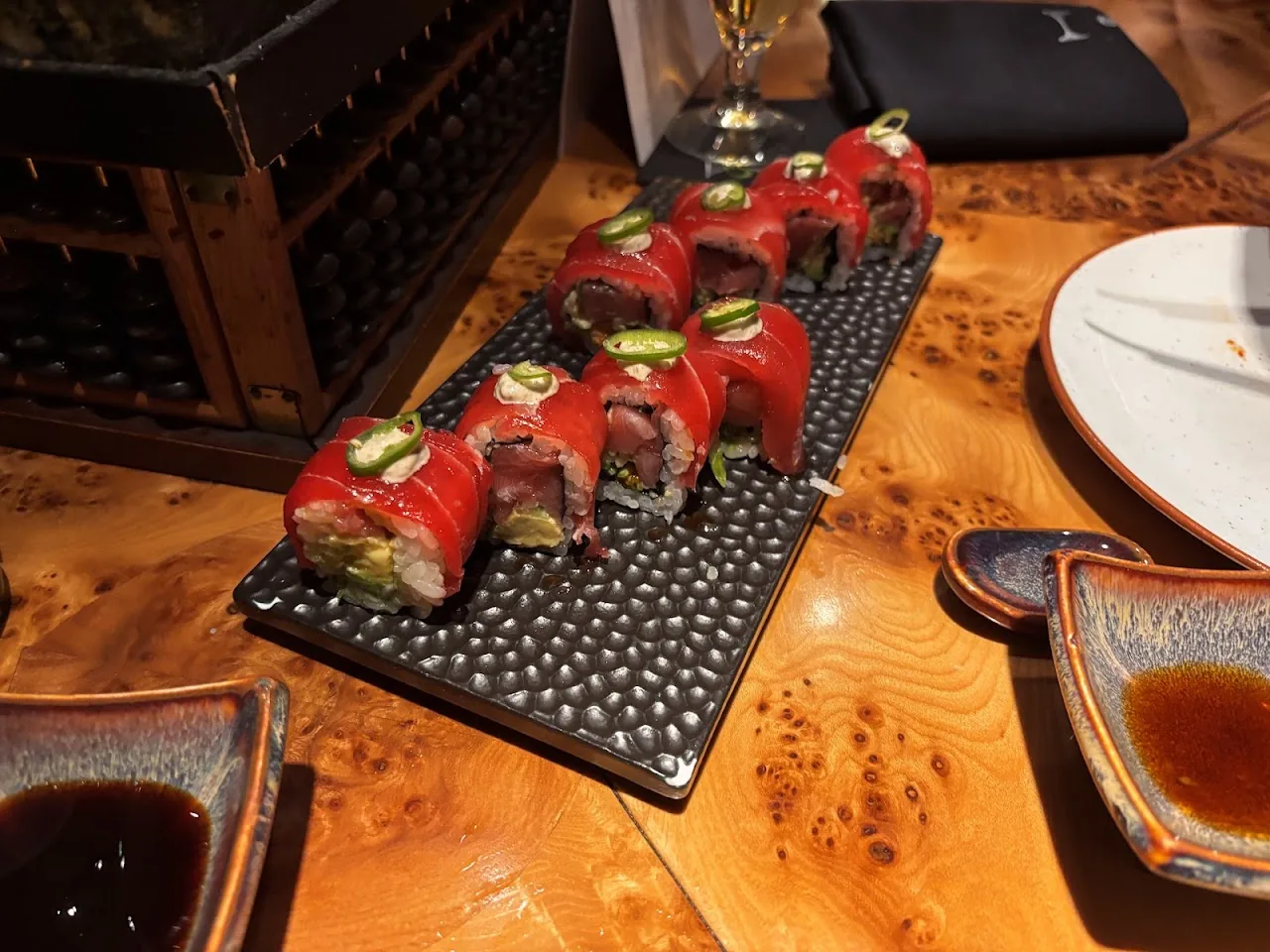 A tray of sushi rolls topped with red garnish