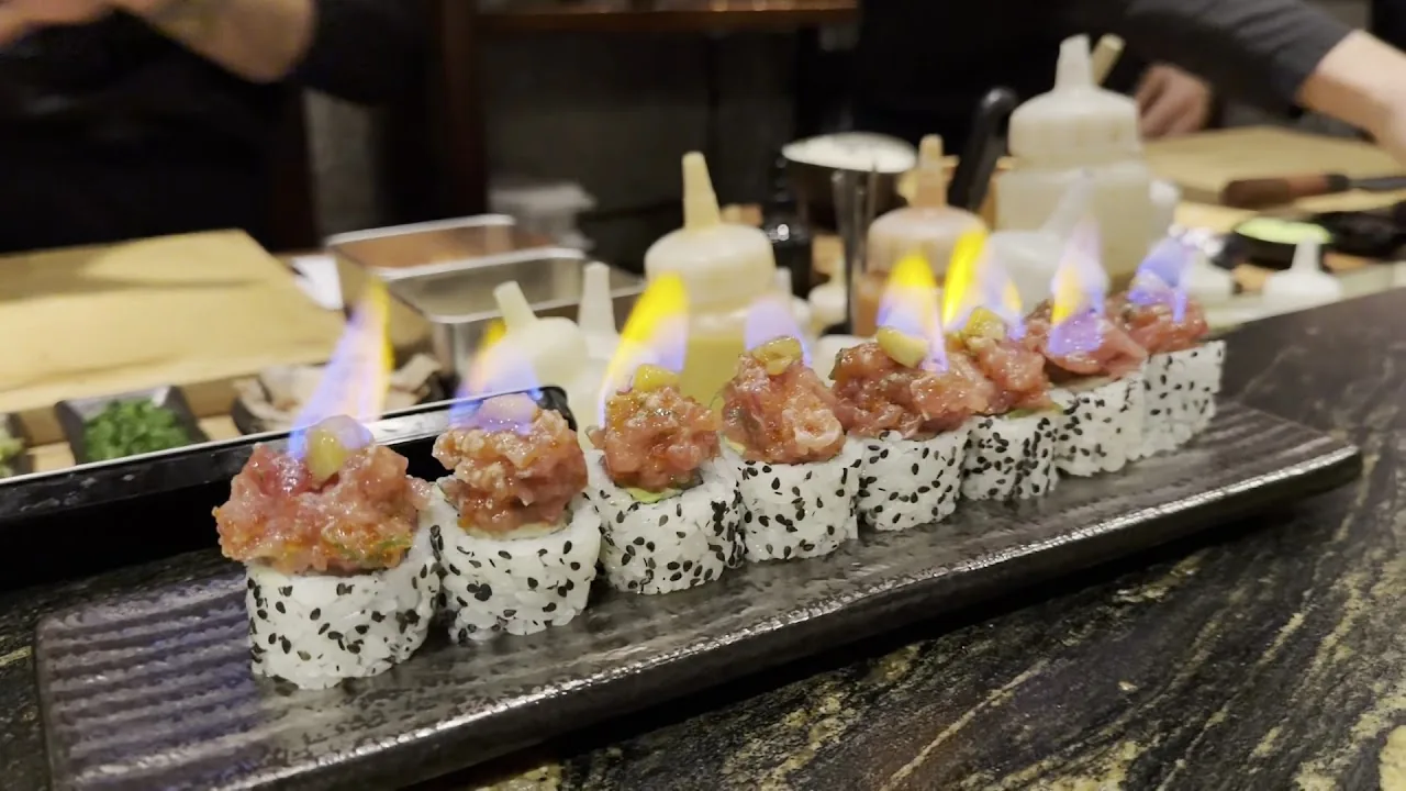 A row of nigiri sushi pieces served flaming on a board