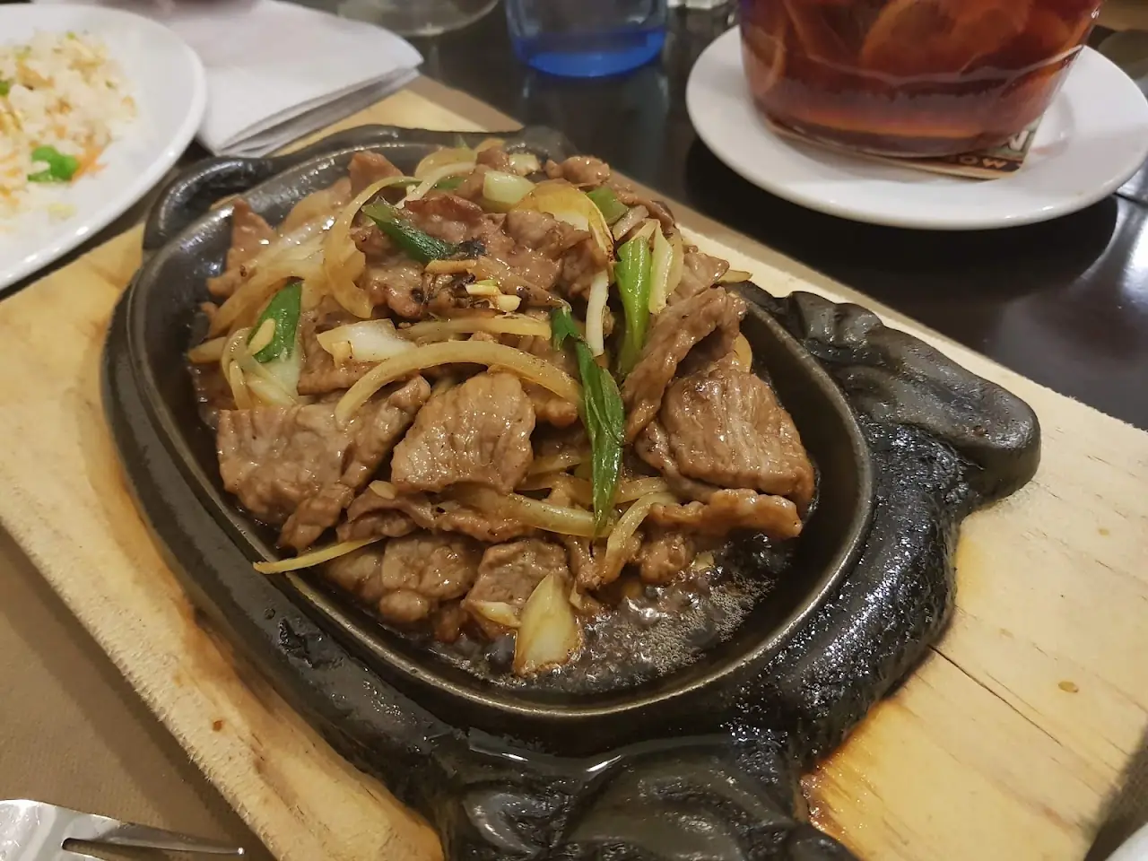 Sizzling beef with onions and scallions served on a hot cast-iron plate, at Restaurant Hoy.