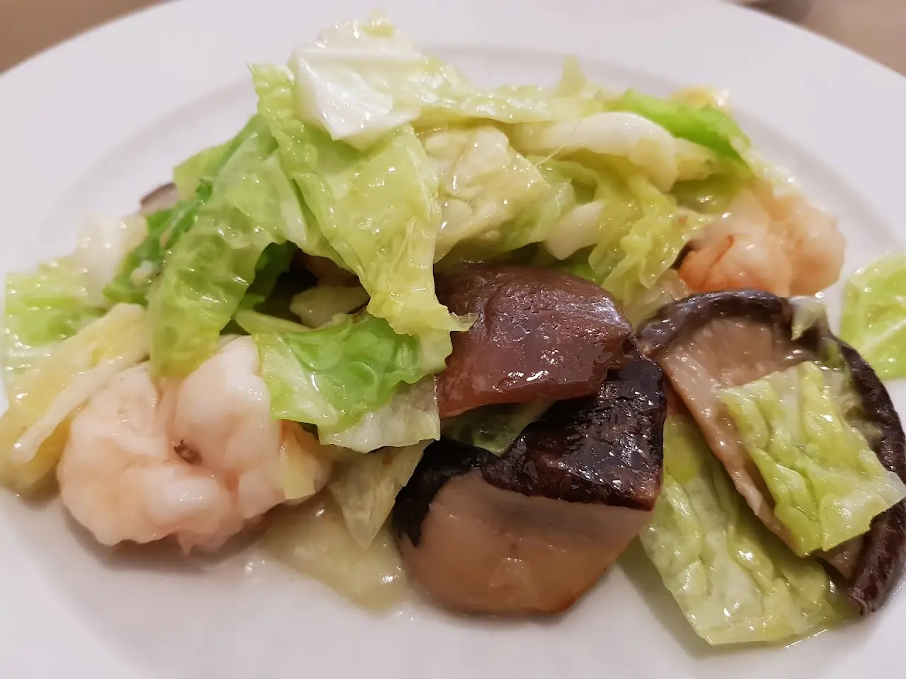 Stir-fried prawns with lettuce and mushrooms on a white plate, at Restaurant Hoy.