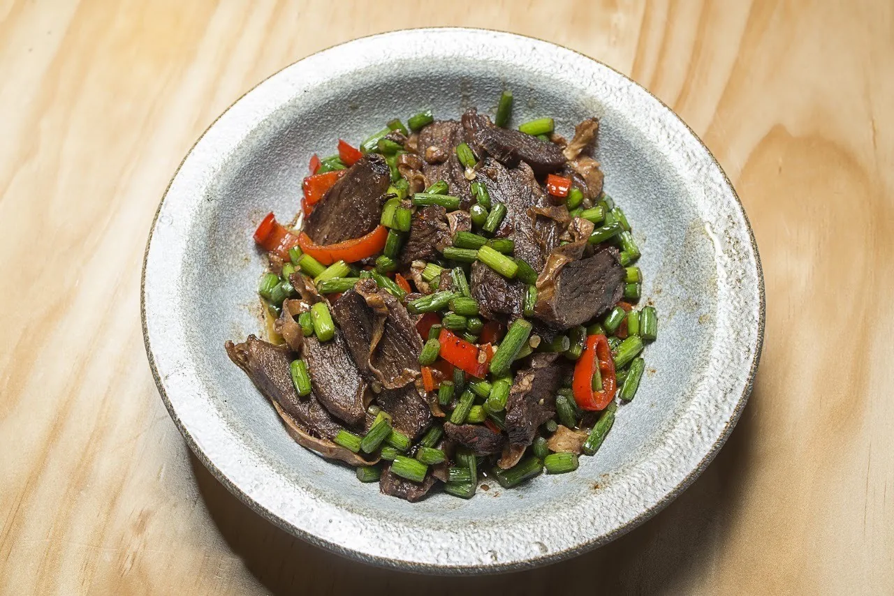A bowl of stir-fried dark meat with chopped green chilli