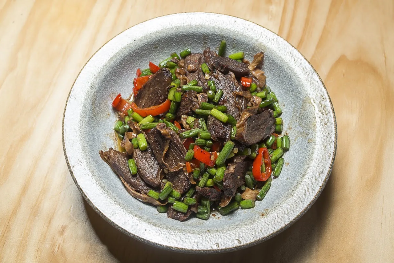 A plate of stir-fried beef with peppers and green beans