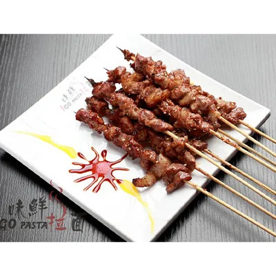 Six grilled meat skewers on a white square plate with chilli and mustard sauce swirls