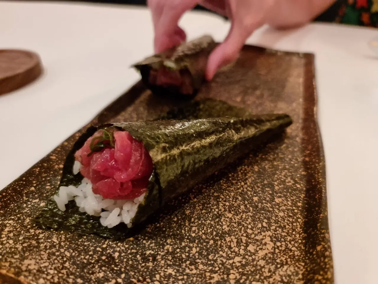 A hand-rolled nori cone filled with rice and a piece of tuna.