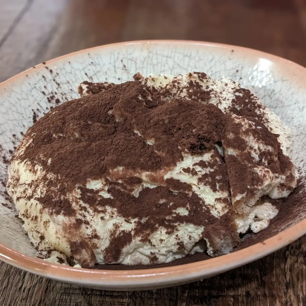 A generous slice of tiramisu dusted with cocoa powder.