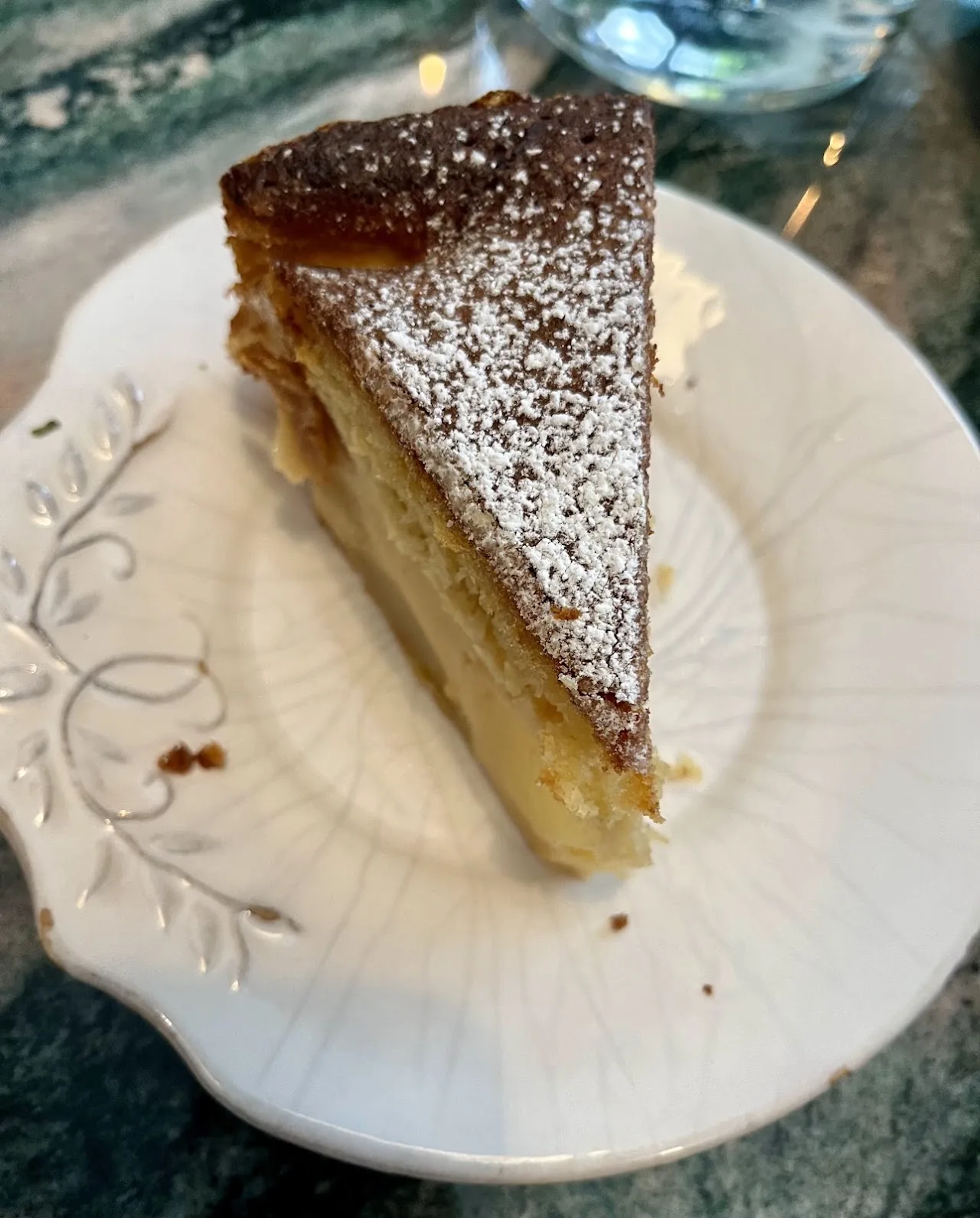 A slice of cake dusted with powdered sugar on a floral plate