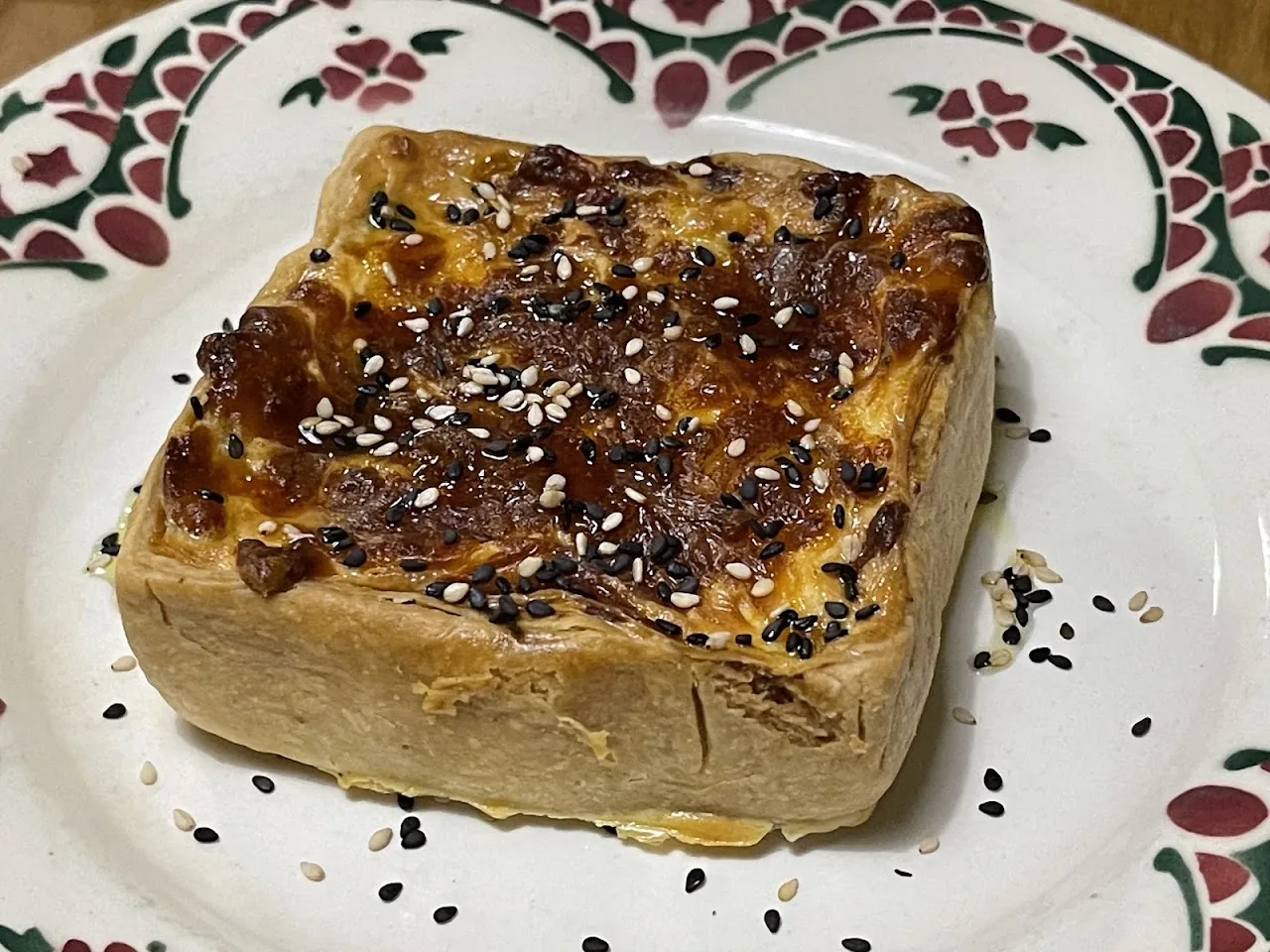 A square pastry topped with sesame and nigella seeds