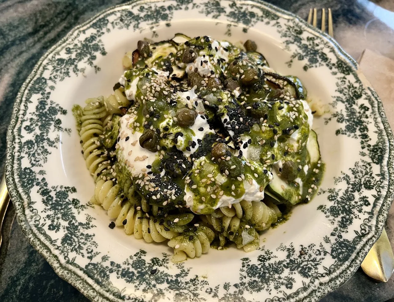 A pasta dish with pesto, courgette, and a dollop of cream
