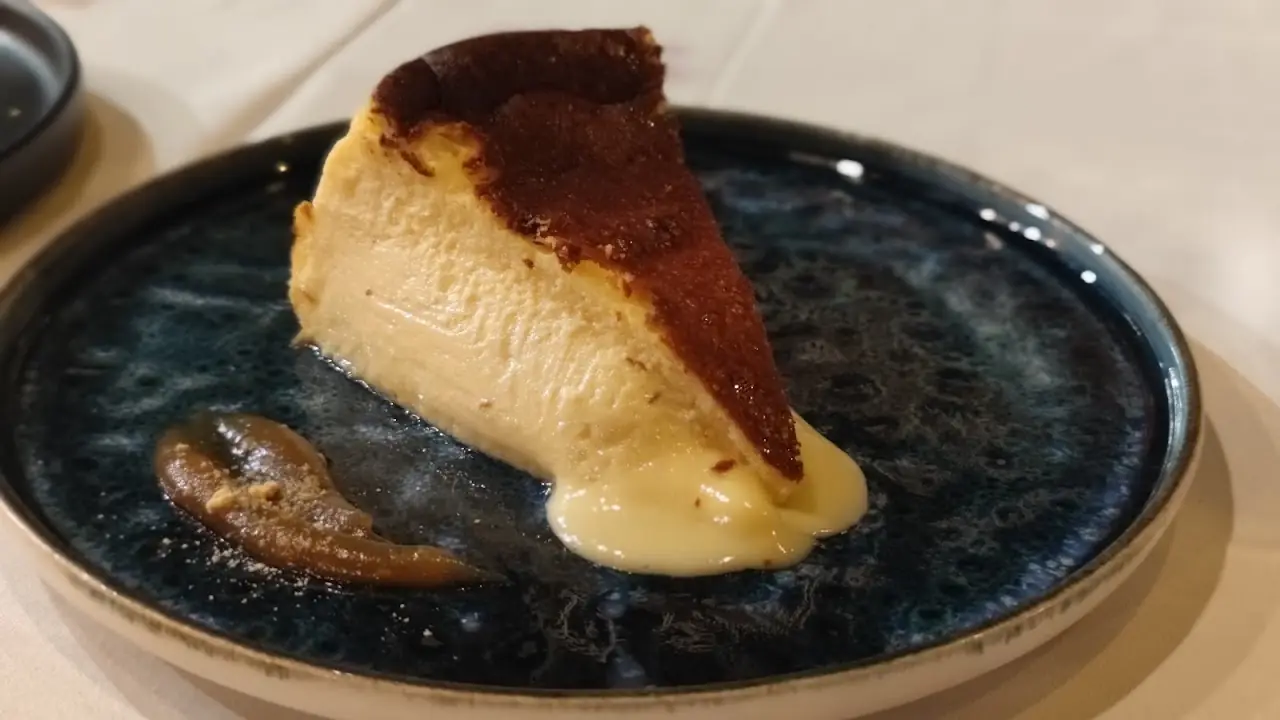 A slice of baked cheesecake with caramel sauce on a blue plate.