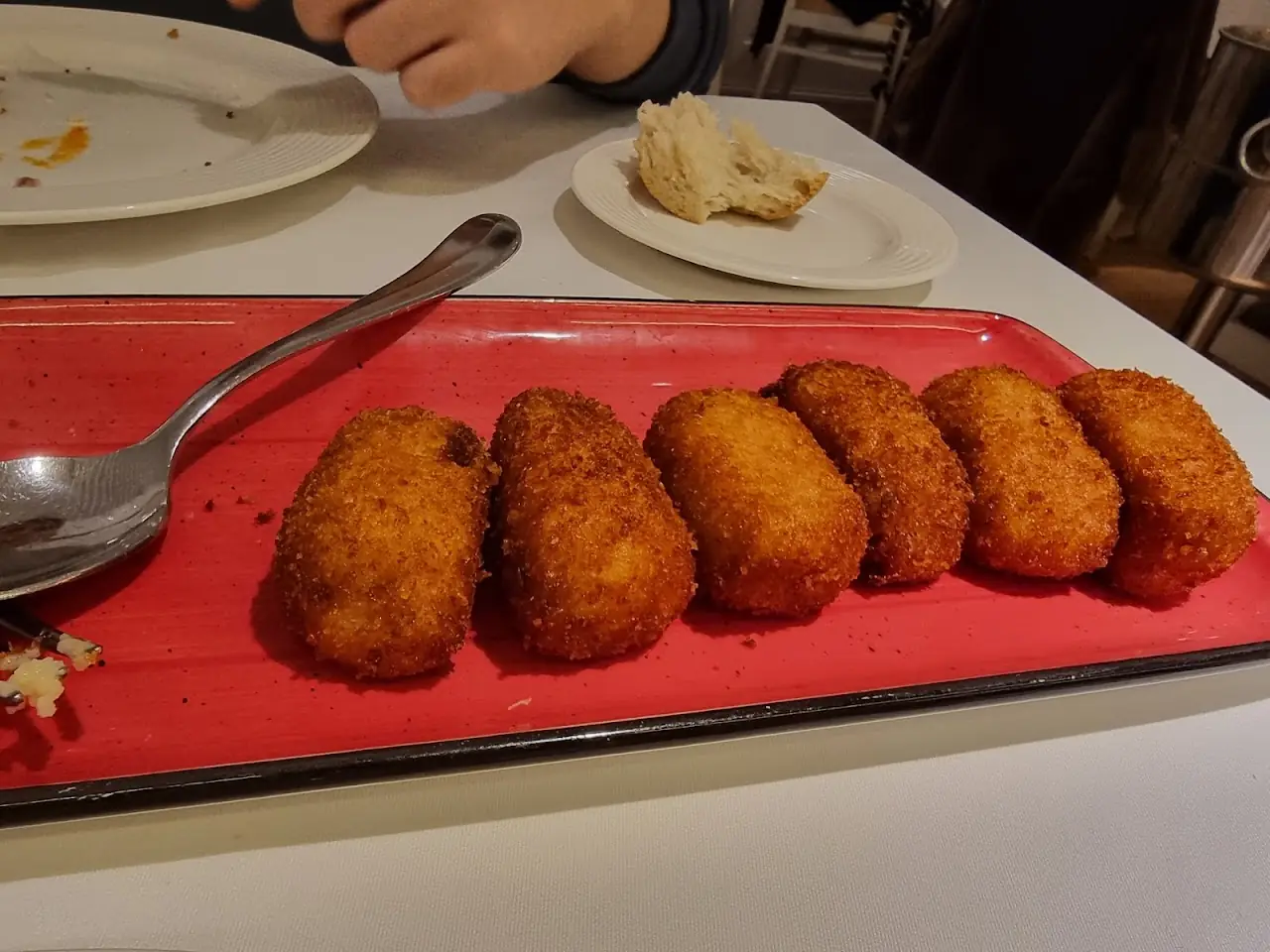 A row of breaded croquettes on a red tray.