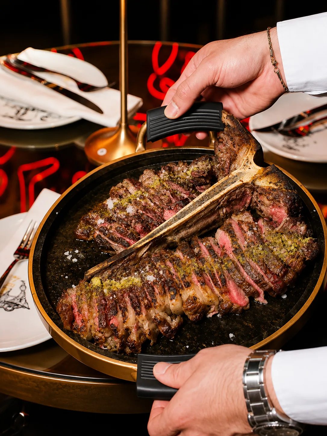 A hand slicing a seared steak on a hot plate