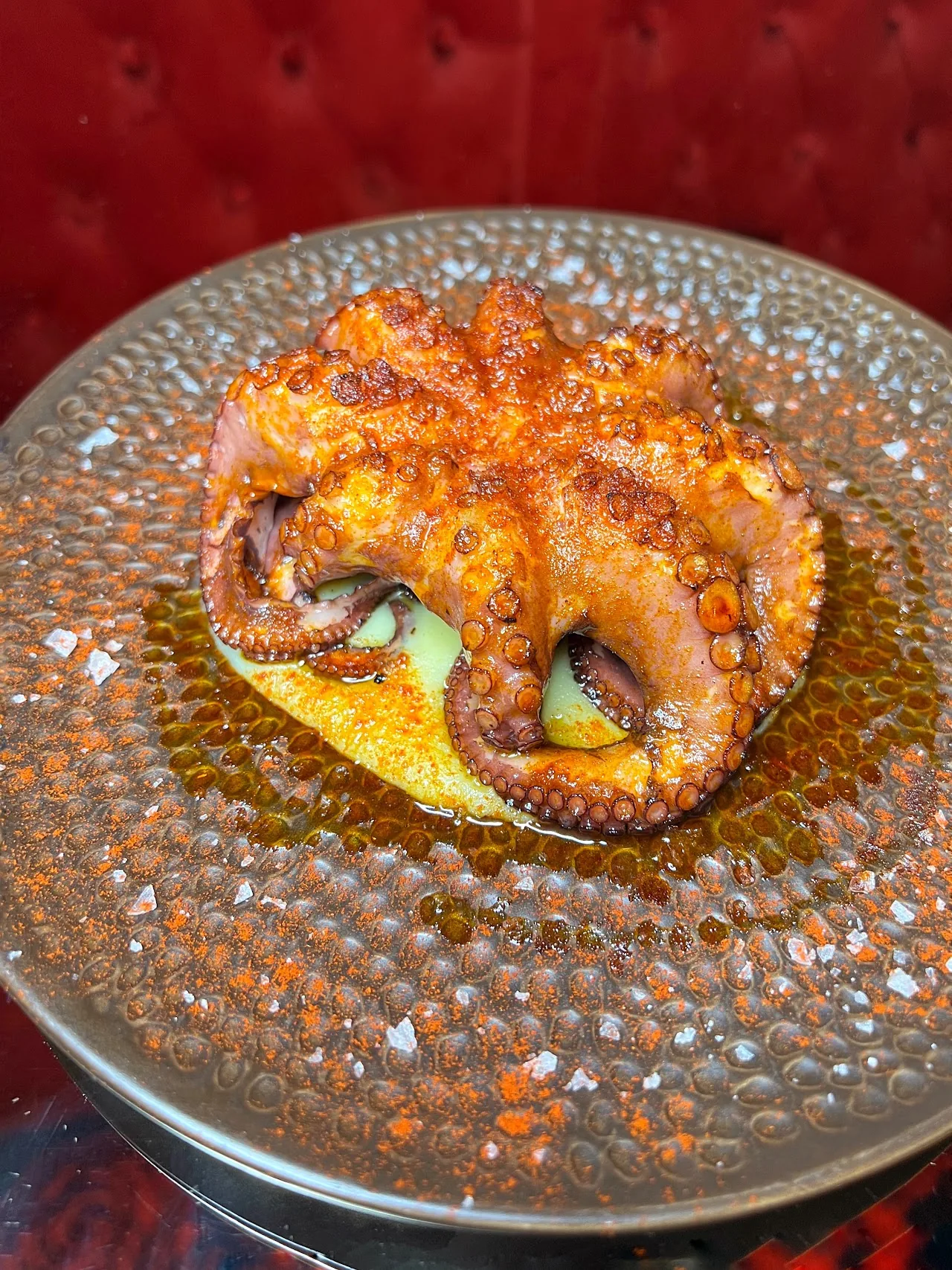 A whole grilled octopus tentacle plated with sauce